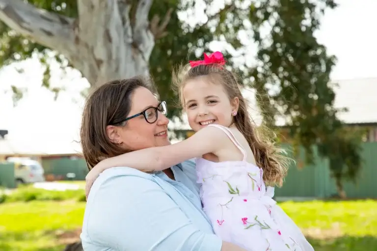 Jenni, a single parent and MyBudget client in Australia, hugging her daughter after creating a personal budget to manage school costs with confidence.